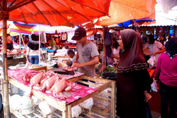 Seorang pedagang ayam potong sibuk melayani pembeli di Pasar Terminal Antokan.