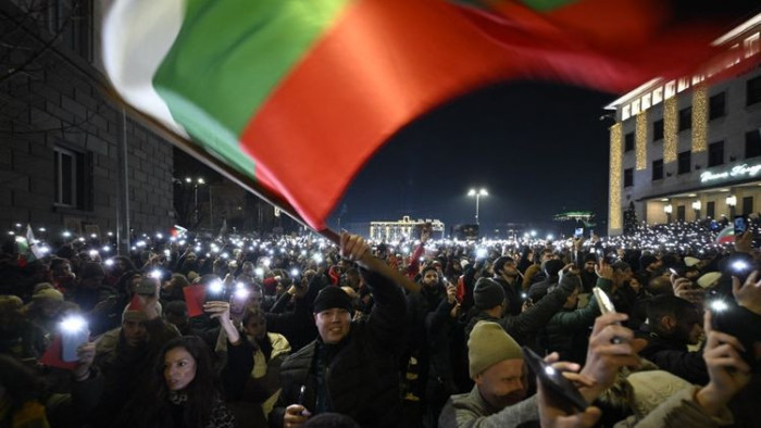 Seorang demonstran mengibarkan bendera Bulgaria selama protes anti-pemerintah di Sofia, Rabu (10/12/2025). Puluhan ribu orang, terutama Gen Z, menggelar protes anti-pemerintah di Bulgaria, memperluas gerakan anti-korupsi yang melanda negara termiskin Uni Erop. Foto AFP